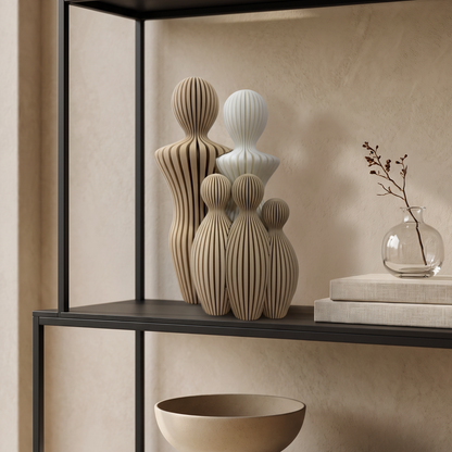 Gepersonaliseerd gezinsbeeldje tweeling en een kind op een zwart wandrek in een warm beige interieur.