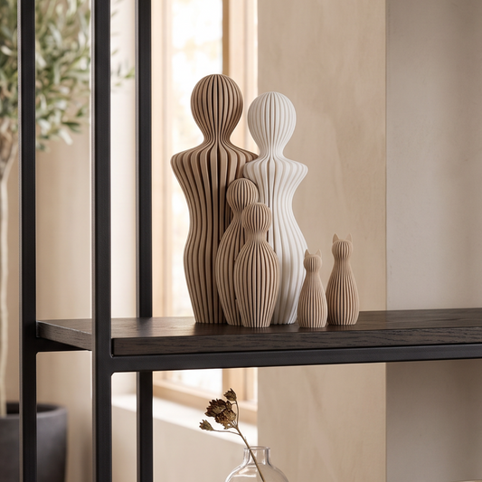 Decoratief gezinsbeeld met twee volwassenen, twee kinderen en twee katten op een zwart wandrek in een warm beige interieur.