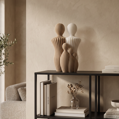 Decoratief gezinsbeeldje met twee vaders en drie kinderen op een zwarte kast in een warm beige interieur.