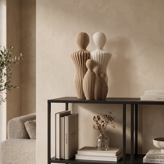Decoratief gezinsbeeldje met twee vaders en drie kinderen op een zwarte kast in een warm beige interieur.
