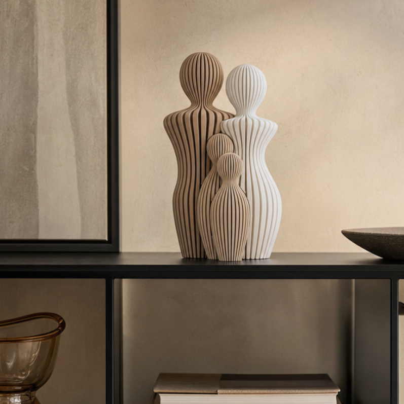 Sfeerfoto van een decoratief gezinsbeeldje op een zwarte kast in een warm beige interieur.