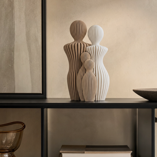 Sfeerfoto van een decoratief gezinsbeeldje op een zwarte kast in een warm beige interieur.
